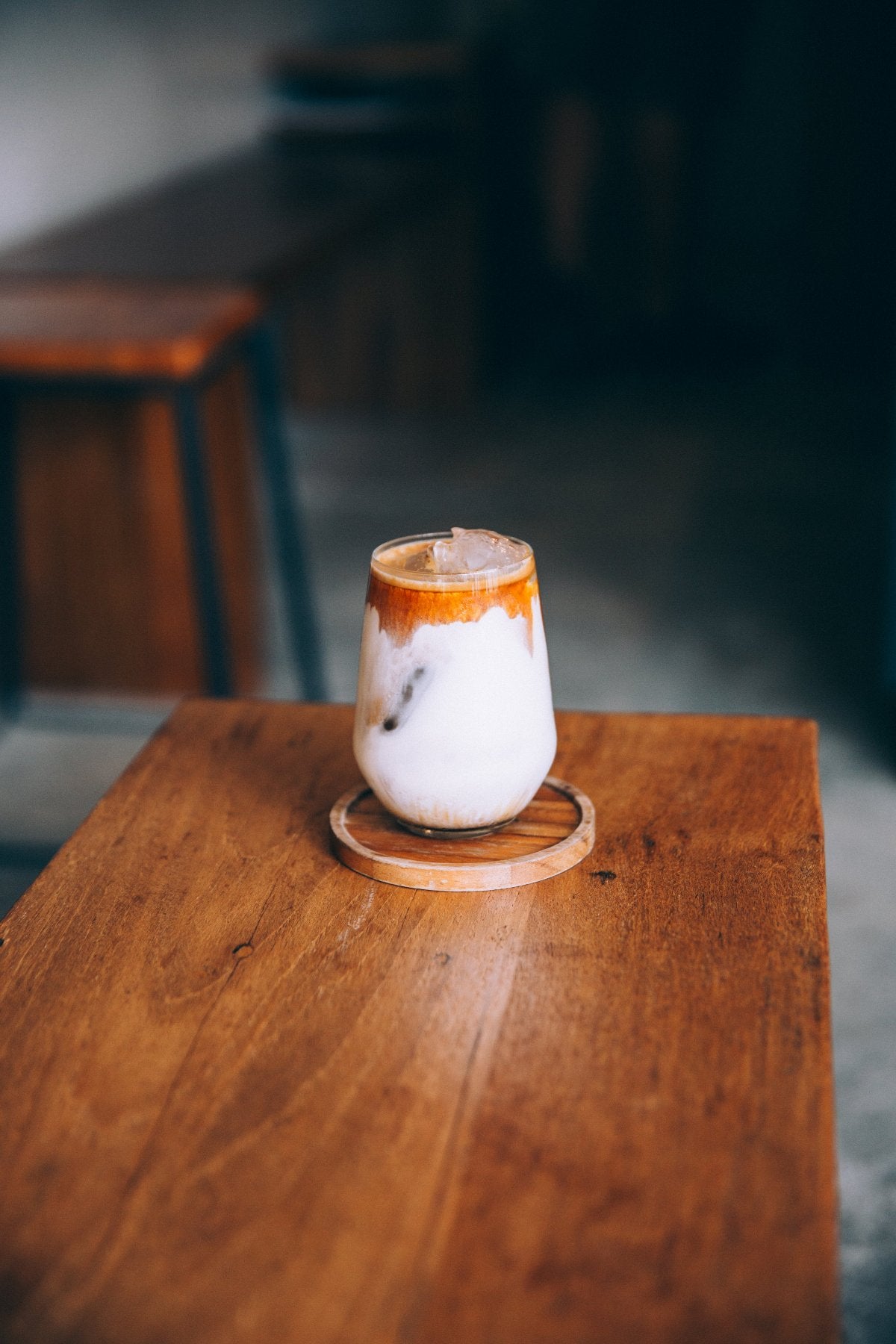 Eiskaffee mit viel Milch auf einem dunkelbraunen Holztisch