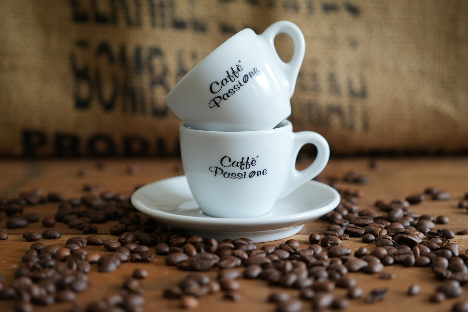 Zwei Caffé Passione Espresso Tassen gestapelt, mit Kaffeebohnen außen herum