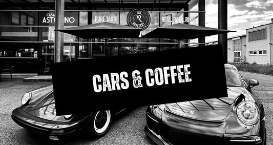 Im Vordergrund steht auf schwarzem Hintergrund der weiße Schriftzug „Cars and Coffee“. Im Hintergrund ist „THE ROASTERY by Caffè Passione“ in Schwarz-Weiß dargestellt, davor befinden sich ein Wasser sowie ein luftgekühlter Porsche.