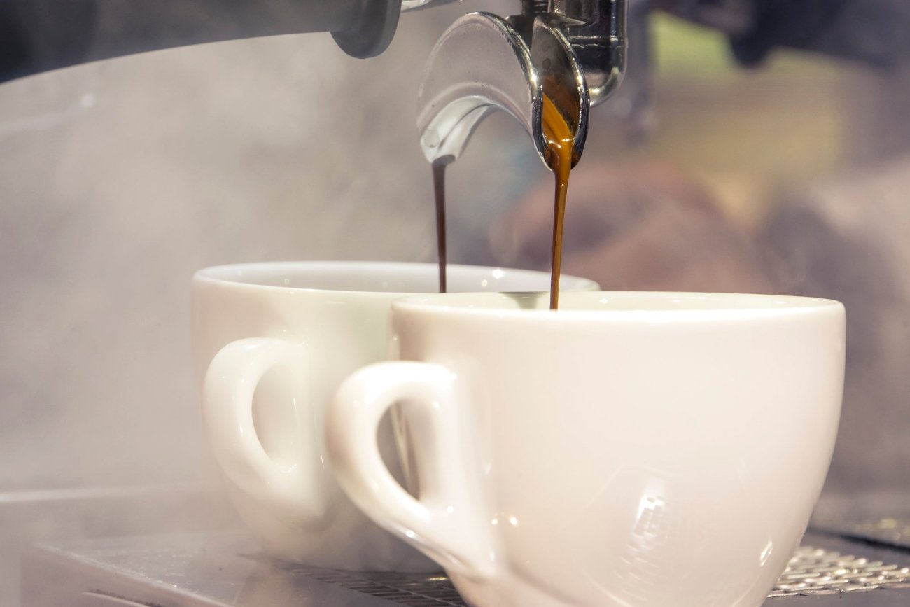 Zwei Kaffeetassen, die gerade durch eine Siebträger-Kaffeemaschine befüllt werden