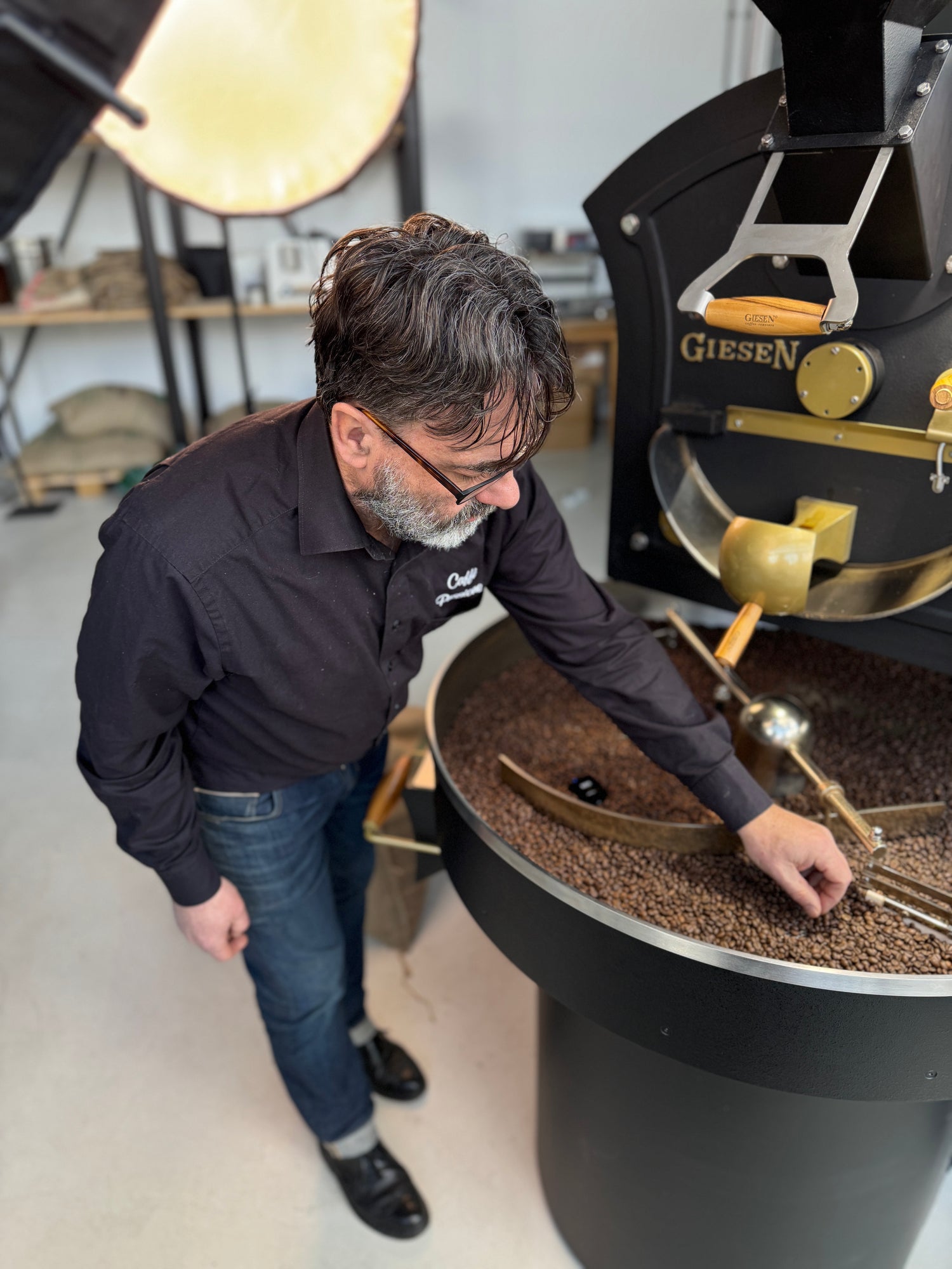 Holger Karl am Gießenröster bei der Kaffeeröstung, prüft sorgfältig die Qualität der Kaffeebohnen nach dem Röstprozess.
