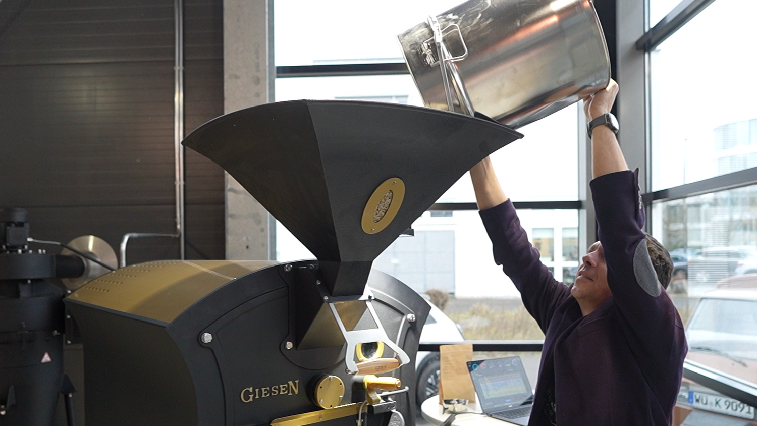 Unser Barista Mario leert die Rohbohnen in den Röster