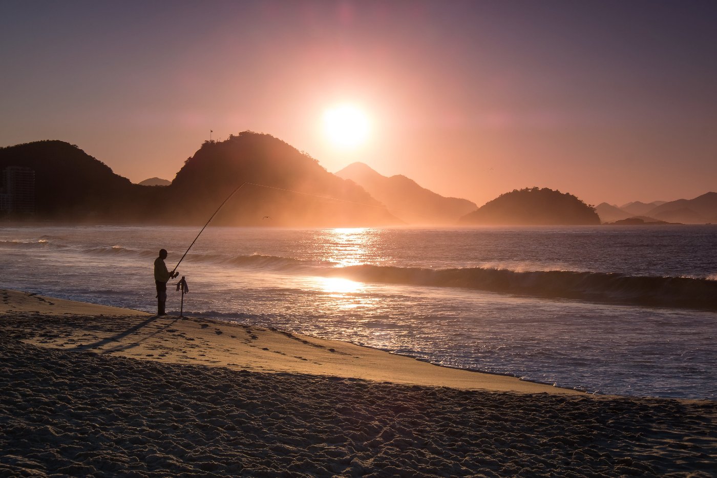 Fischer am Strand bei Sonnenuntergang am angeln