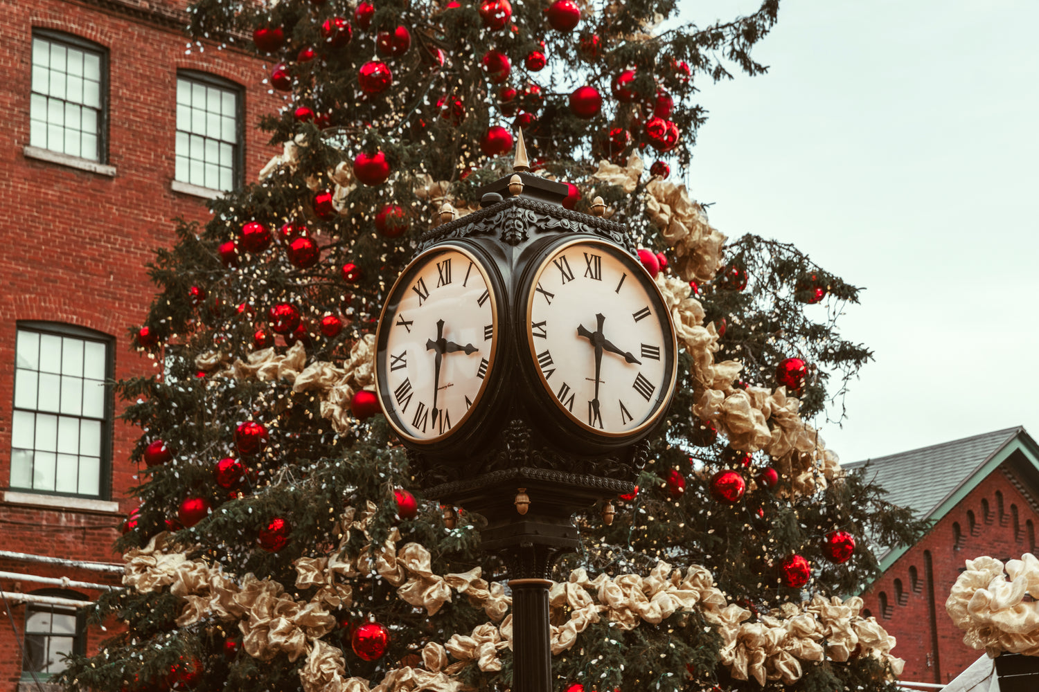 geschmückter Weihnachtsbaum, vor dem eine Uhr steht